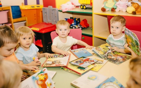 Дети детского сада сидят за столом с книгами